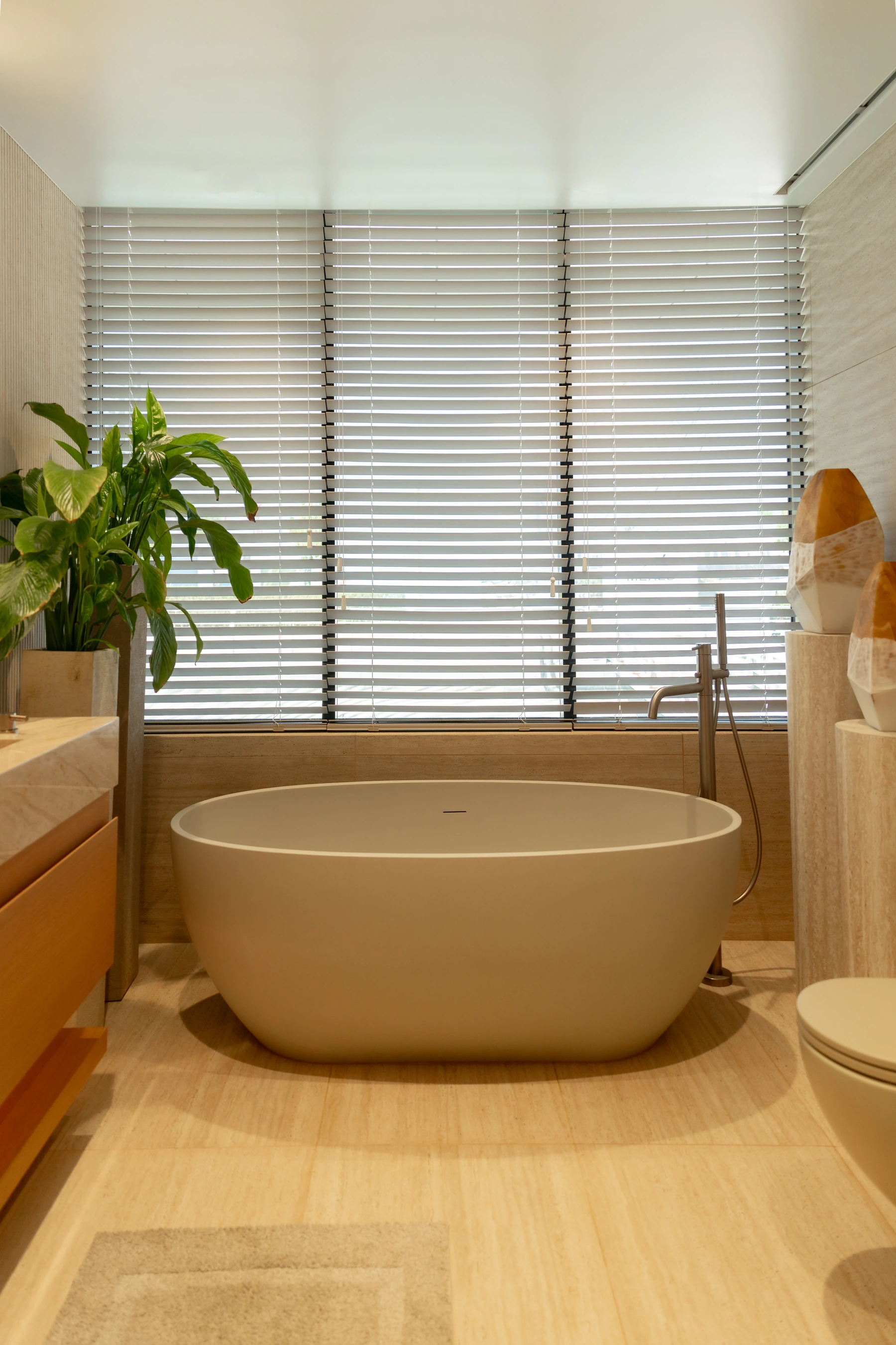 A freestanding bathtub in a warm stone bathroom