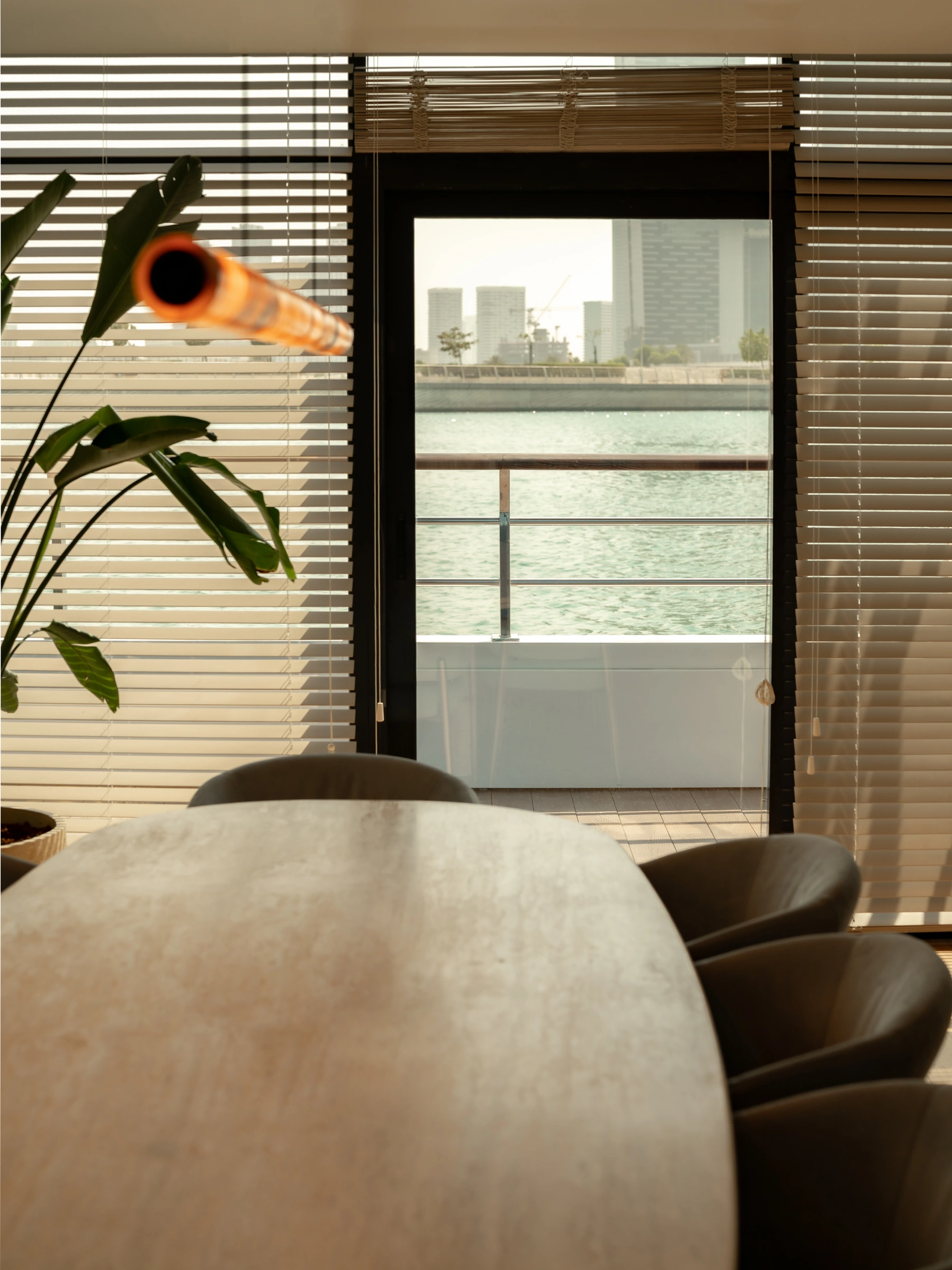 A dining table beside full-height windows overlooking the water