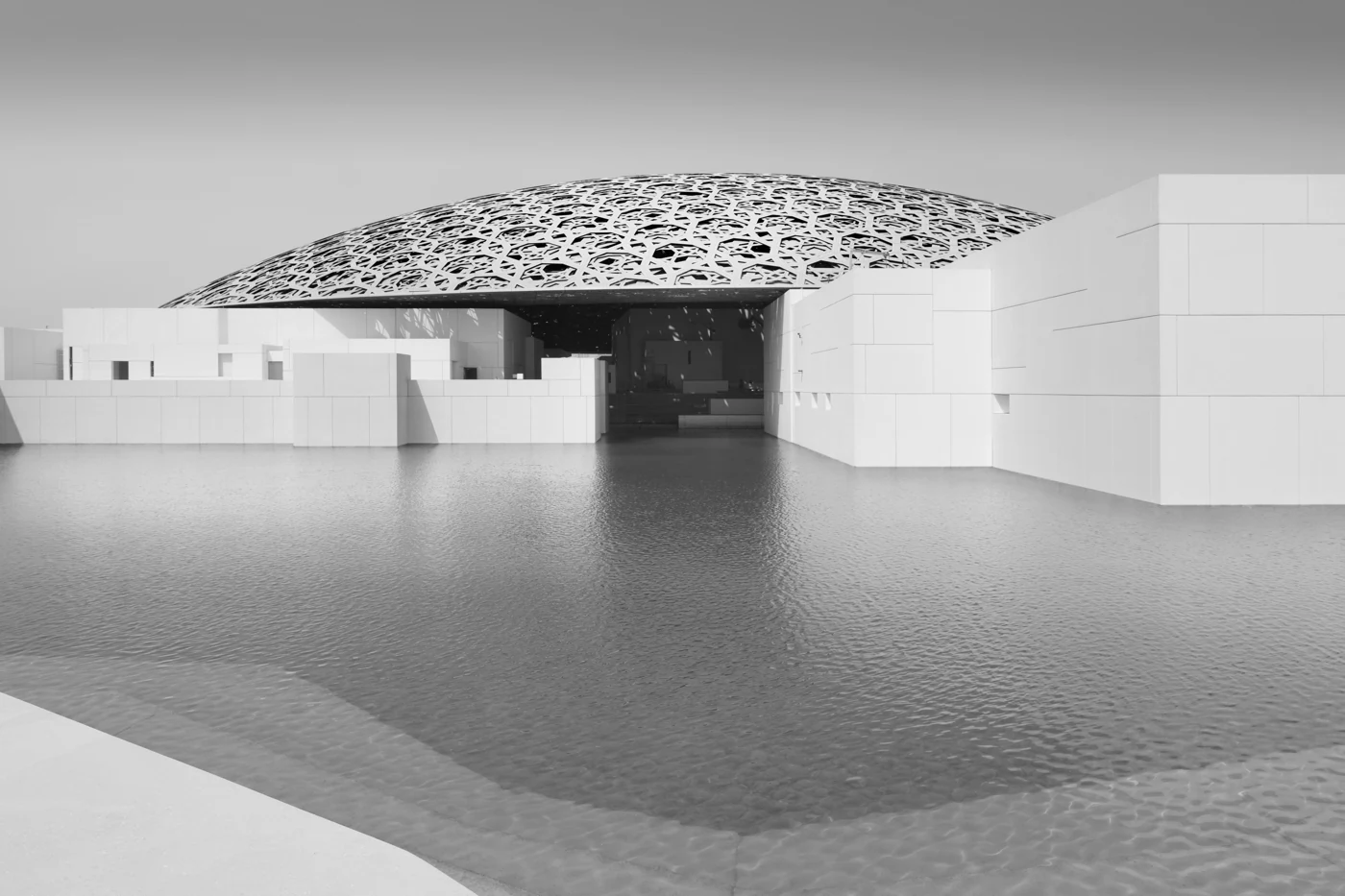 The architectural dome of Louvre Abu Dhabi beside the water